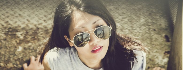 Young woman sitting relaxed and looking up while wearing sunglasses